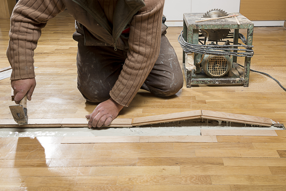 A carpenter working to fix hard wood flooring