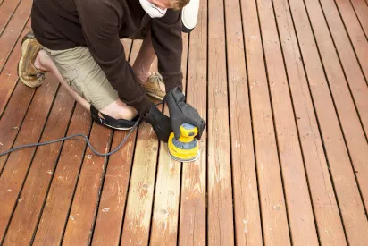 Someone is sanding a deck with a palm sander