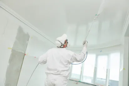 Man painting ceiling of home with an electric paint gun