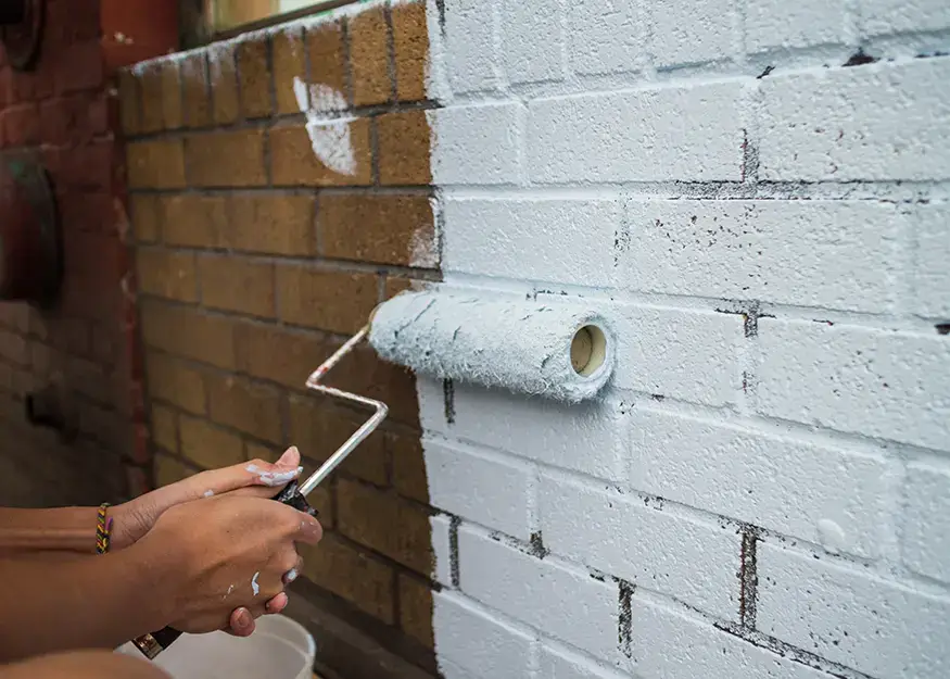 Someone using a roller to paint brick