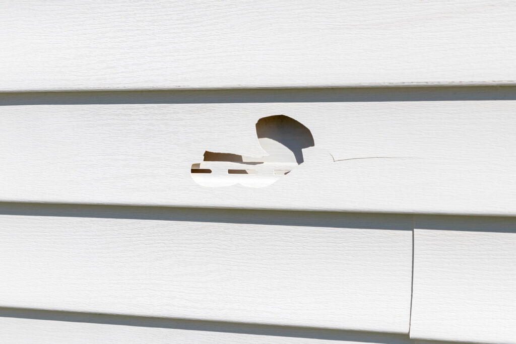 A hole is punctured in vinyl siding after hail