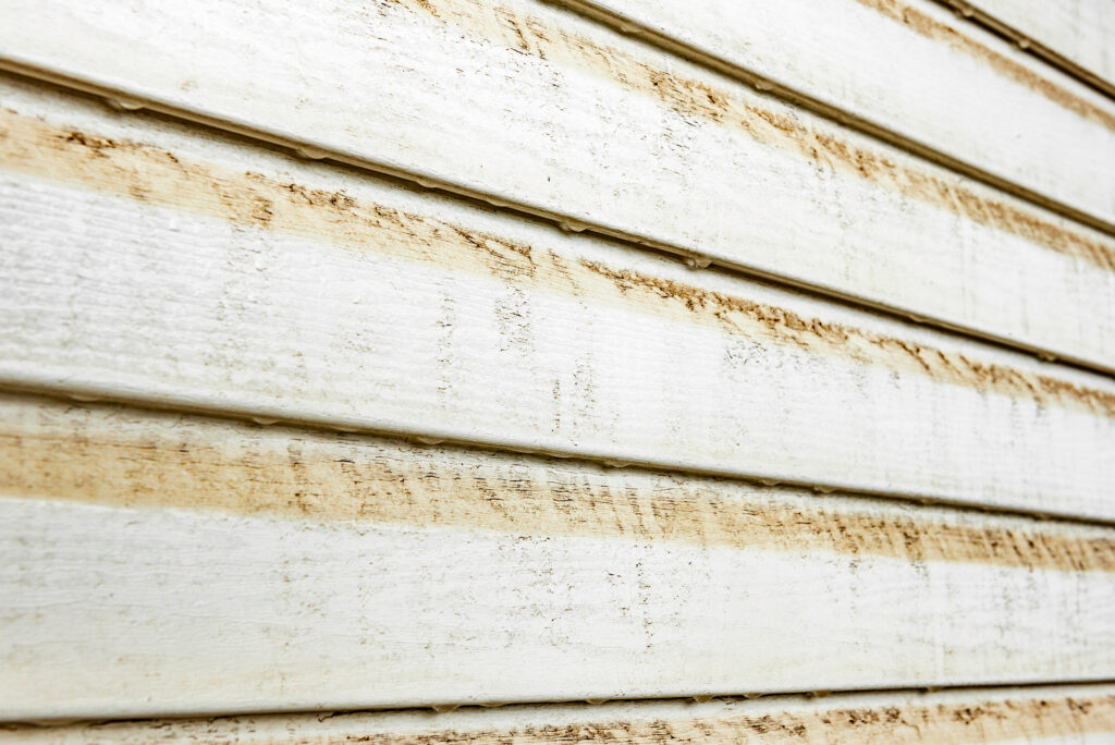 White siding with yellow-brown stains